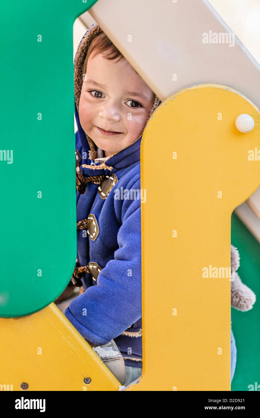 Un giovane ragazzo salire le scale di una diapositiva in un parco giochi Foto Stock