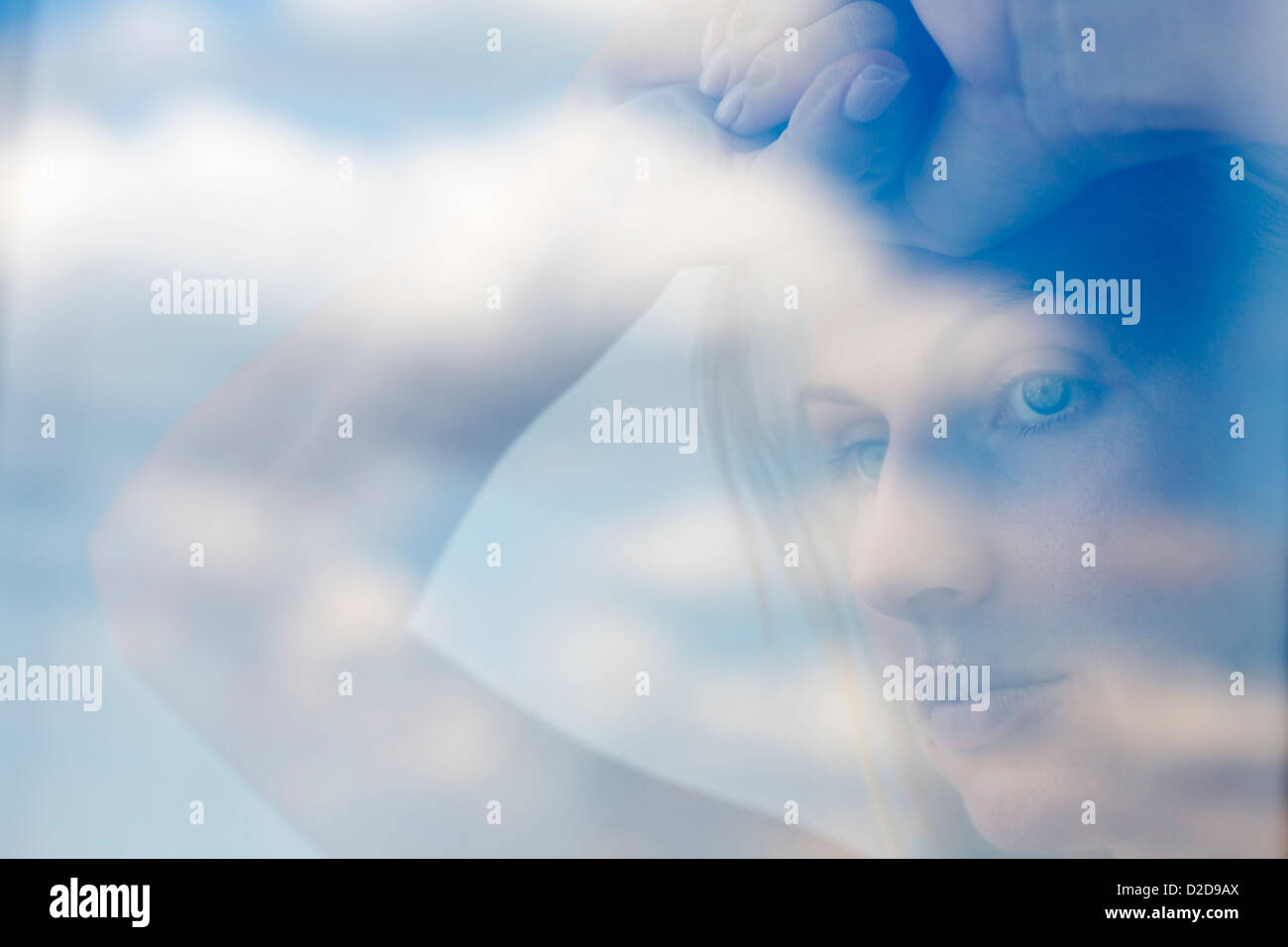 Una seria donna cerca contemplatively fuori una finestra Foto Stock