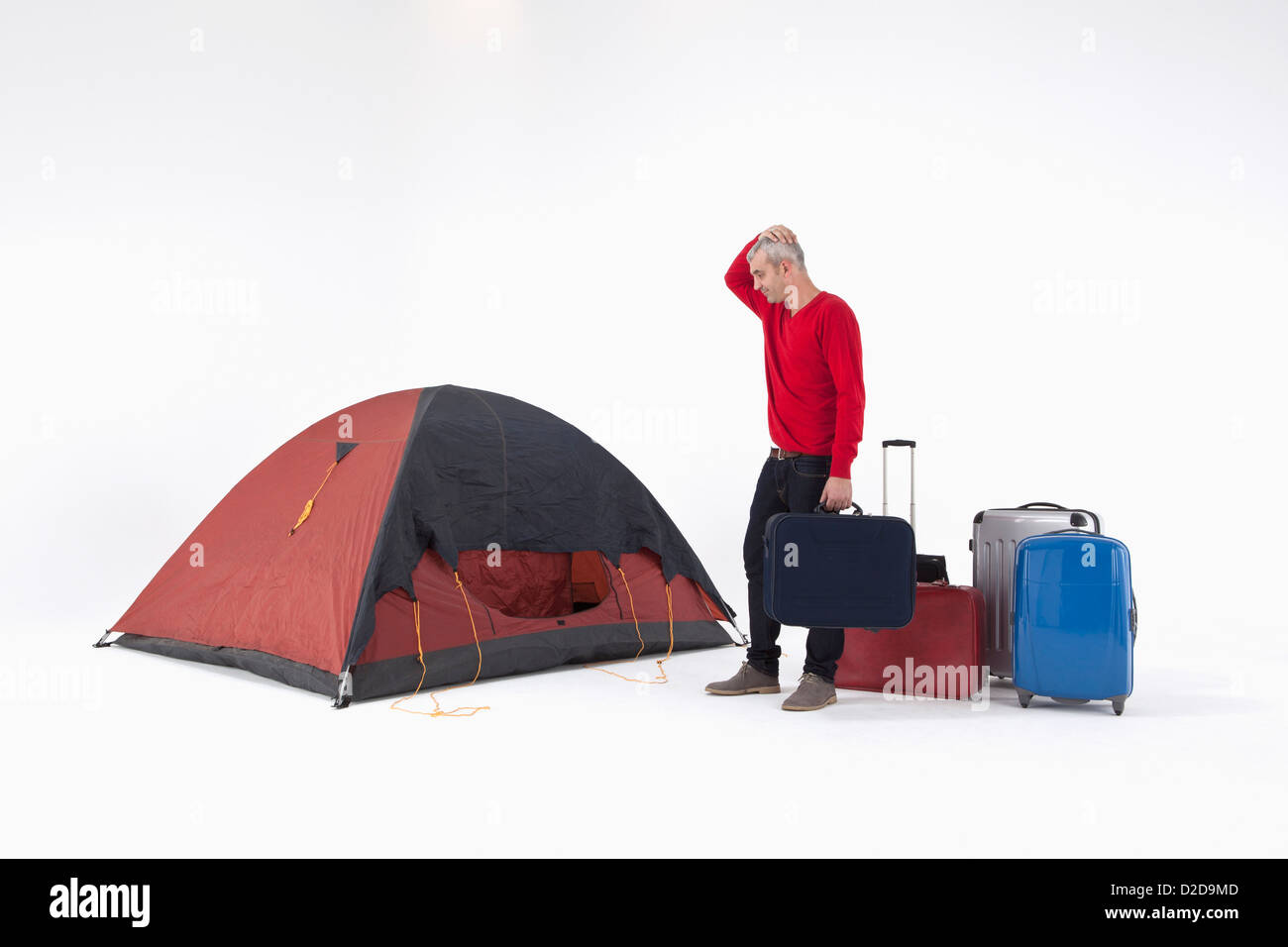 Un uomo infelice con carichi di bagagli guardando una tenda con incertezza Foto Stock
