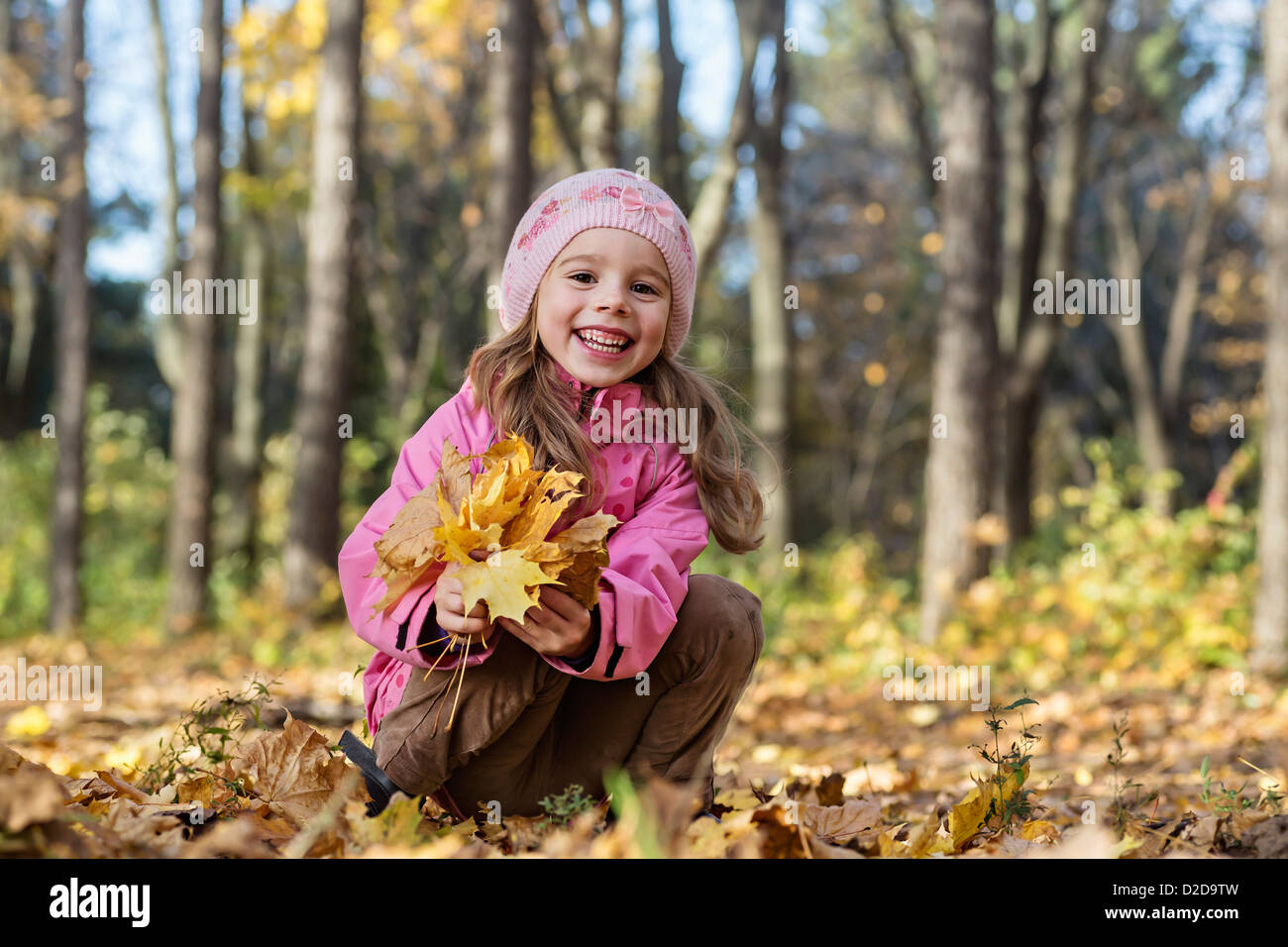 Un vivace ragazza di prelevare le foglie di autunno in una zona boschiva Foto Stock
