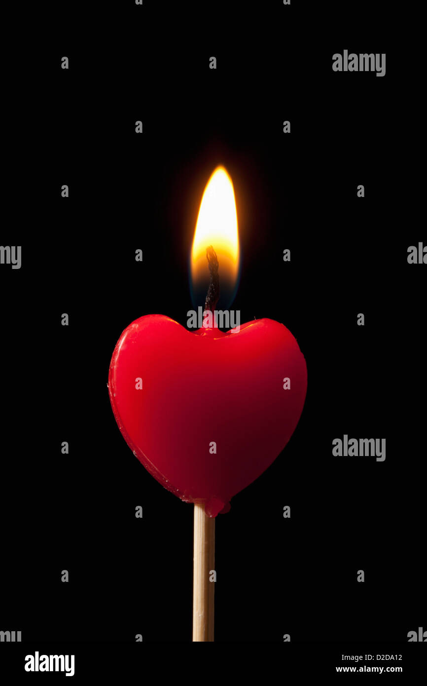 Un acceso a forma di cuore sulla candela un bastone Foto Stock