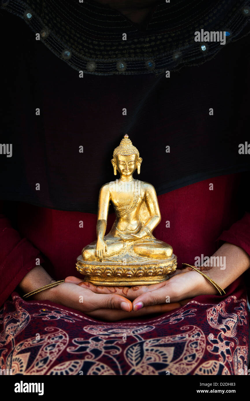 Golden statua del Buddha seduto sulle mani di una ragazza indiana. India Foto Stock
