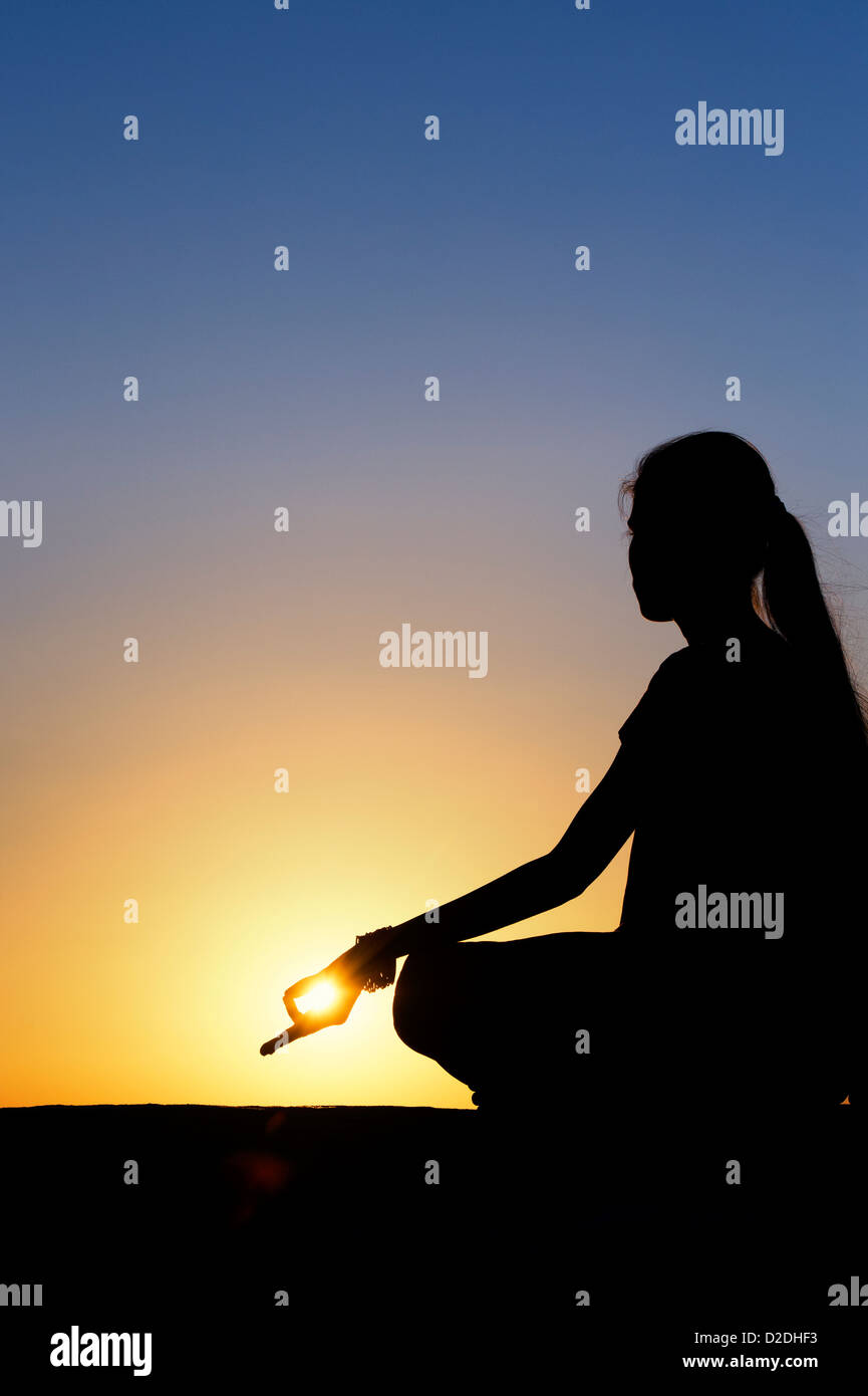 Sunset silhouette di una ragazza indiana meditando. Andhra Pradesh, India Foto Stock