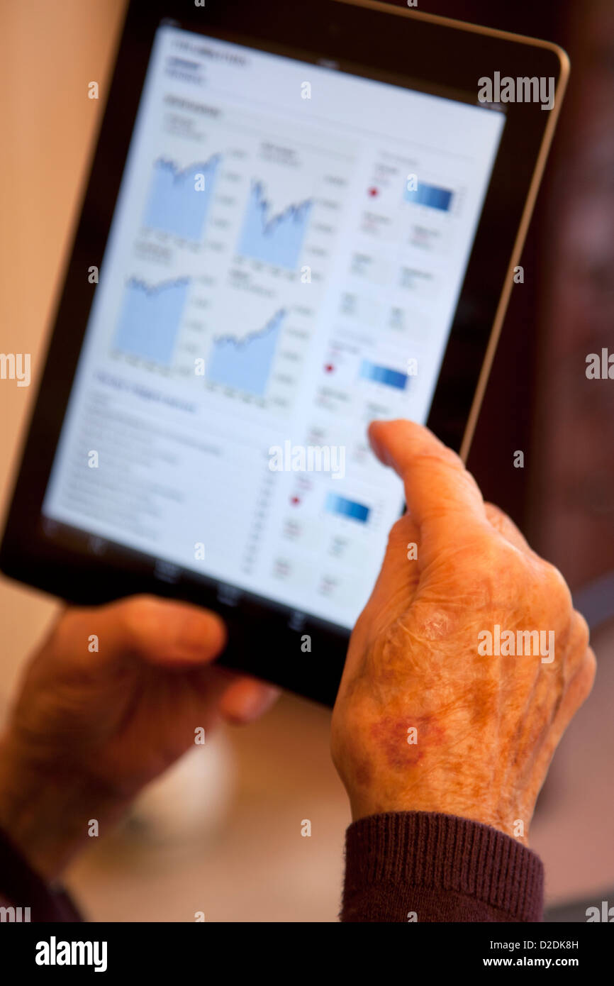 Vecchia persona guardando i suoi investimenti, scorte e condivide in linea con un computer tablet ipad Foto Stock