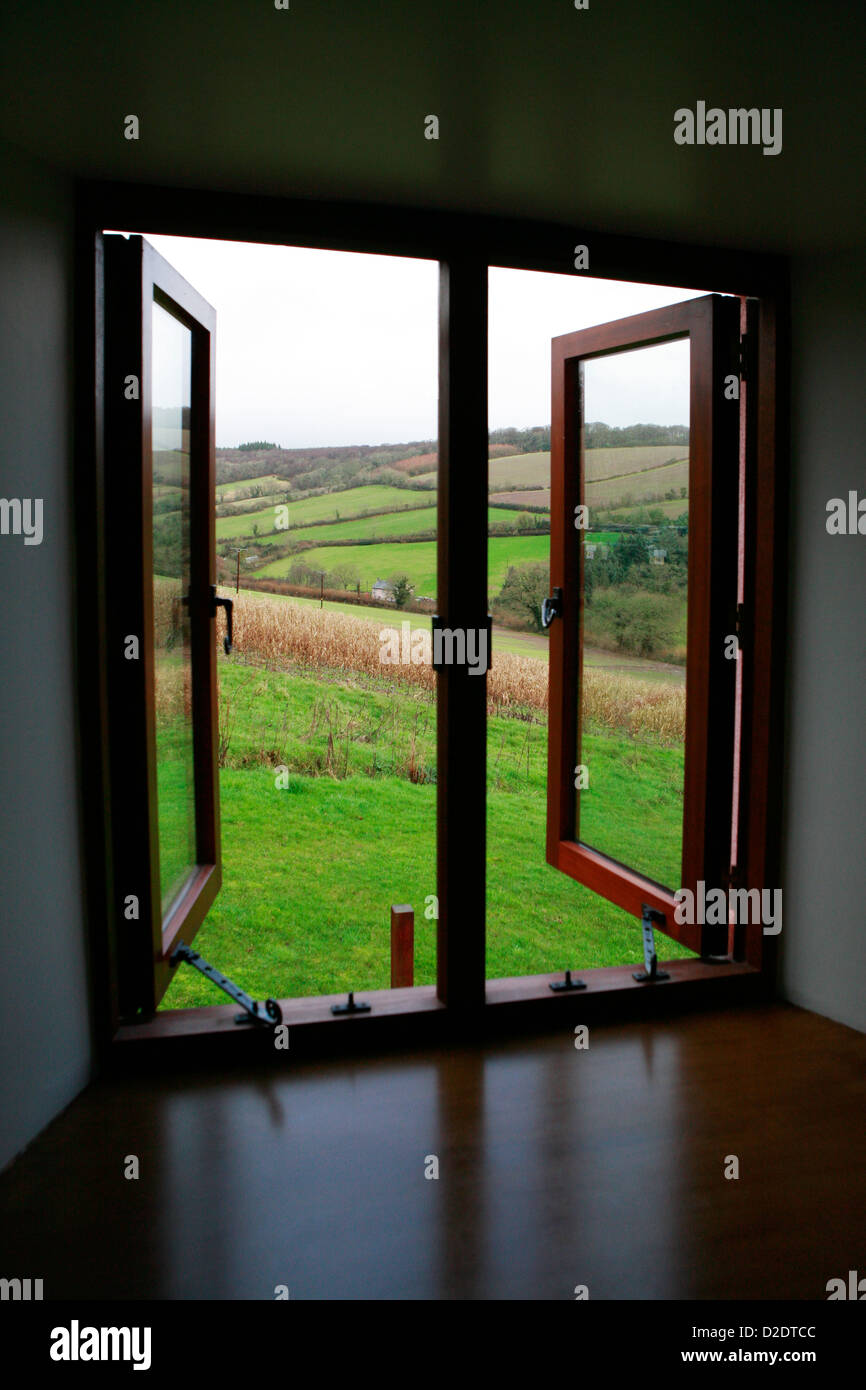 Una vista da una finestra aperta della valle campagna in Ashcombe, Devon, Inghilterra. Paesaggio invernale con una sola casa visibile Foto Stock