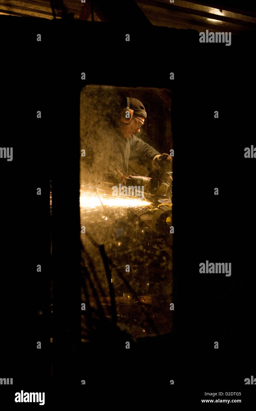 Immagine di un uomo preso attraverso una finestra di lui usando il disco elettrico mola di taglio creando un sacco di scintille da red hot metal. Foto Stock