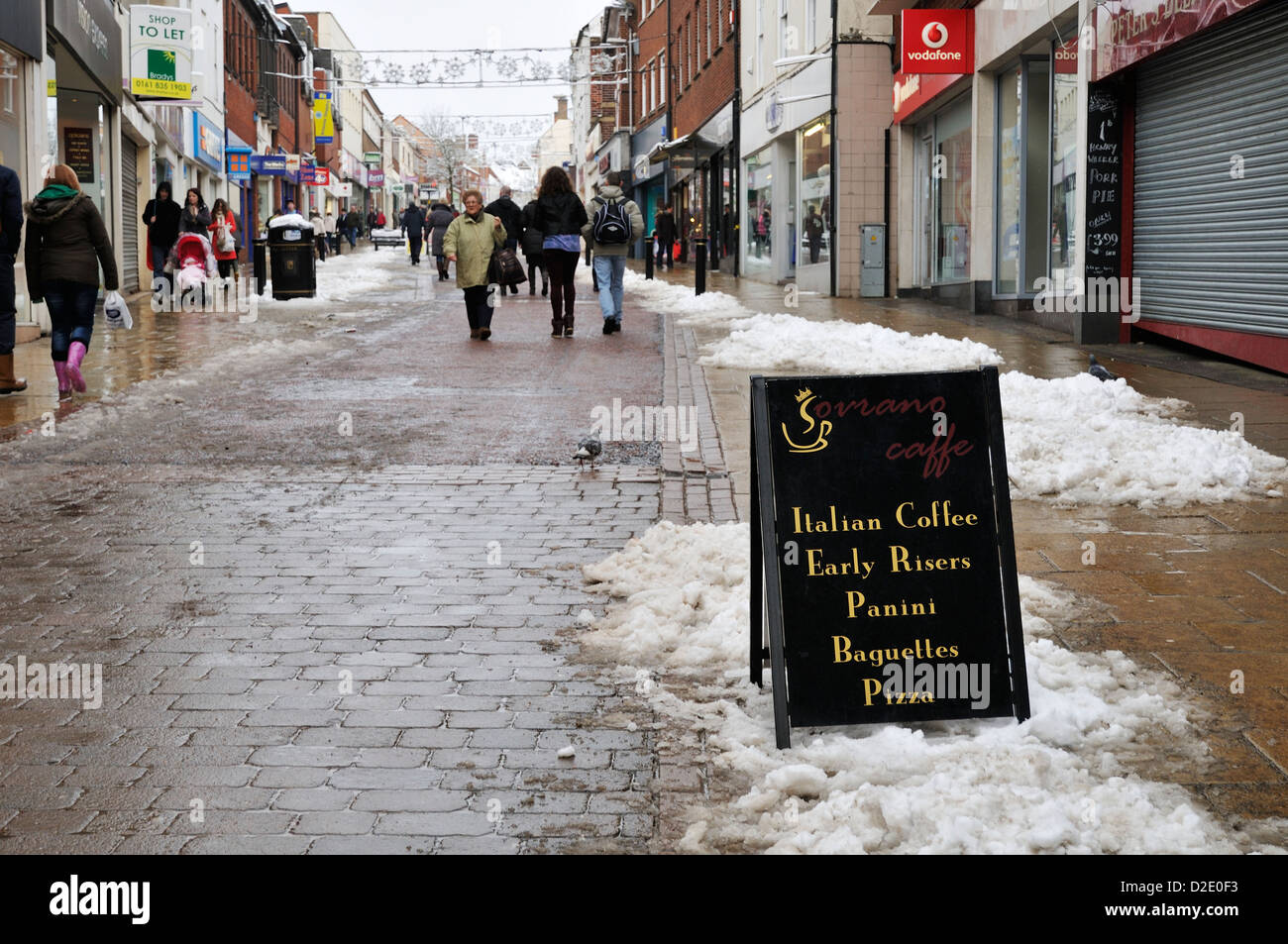 Gli amanti dello shopping camminano lungo Castle Street a Hinckley in una giornata invernale innevata Foto Stock