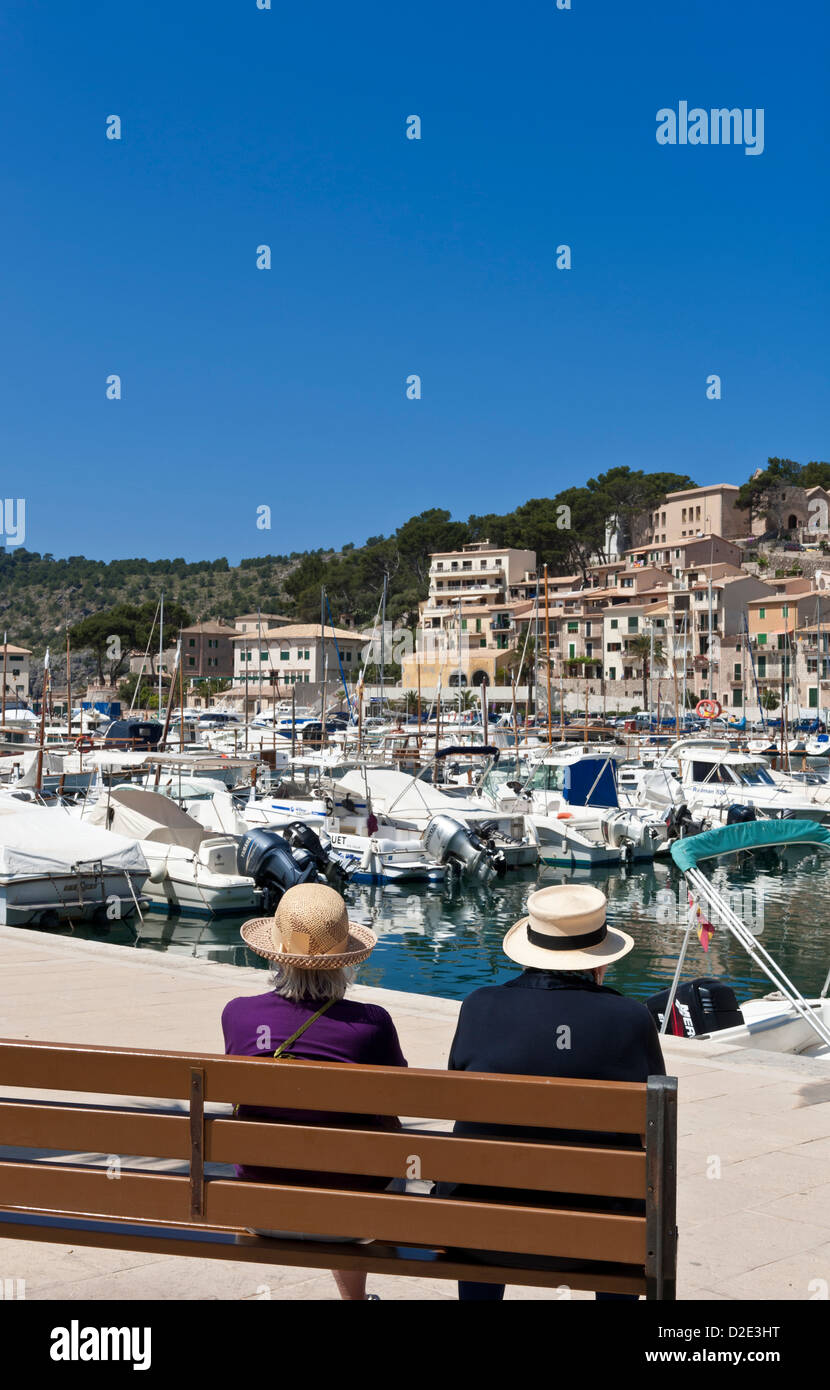 MAIORCA anziani vacanza Spagna due signore con cappelli di paglia sedute su una panchina insieme godendo della vista del porto Port de Soller Palma de Mallorca Spagna Foto Stock