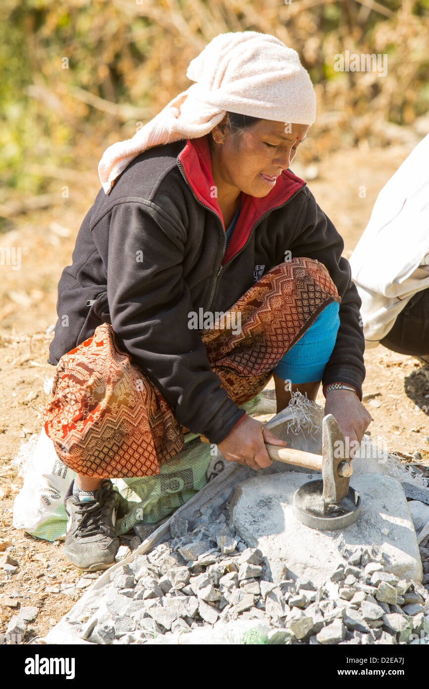Una donna Nepalese la frantumazione di pietra con un martello, foothills dell'Himalaya, Nepal. Foto Stock