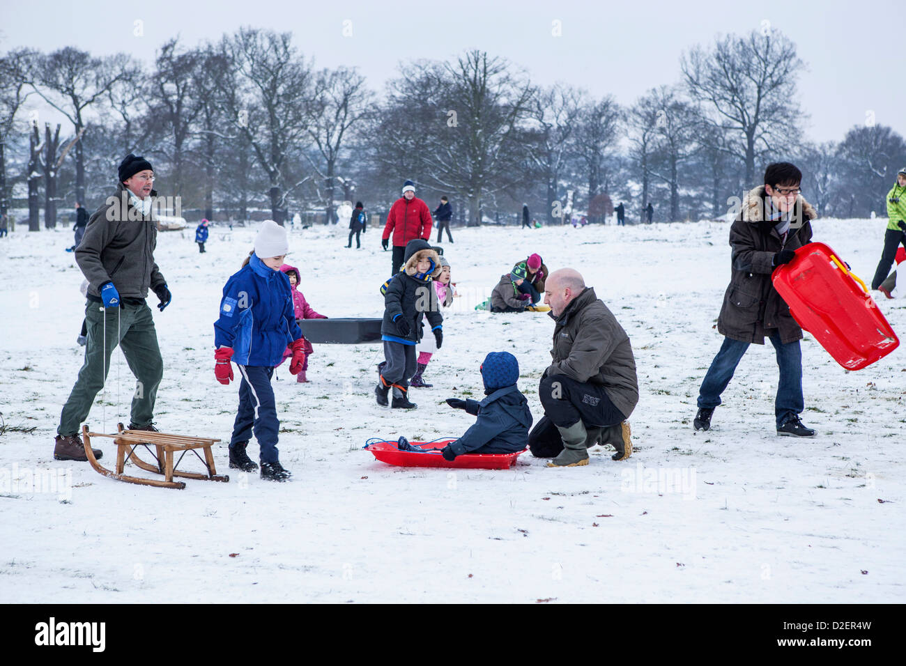 Famiglie con animali domestici e slittini godendo la neve in presenza di neve il parco di Richmond in freddo inverno,Richmond upon Thames, Greater London, Regno Unito Foto Stock