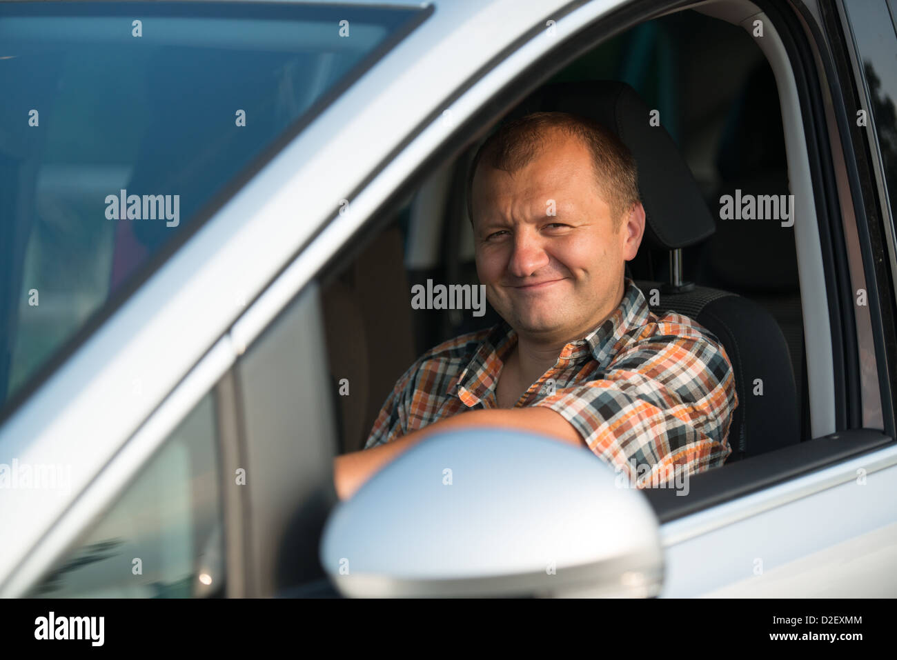 Felice giovane uomo alla guida di una vettura e sorridente Foto Stock