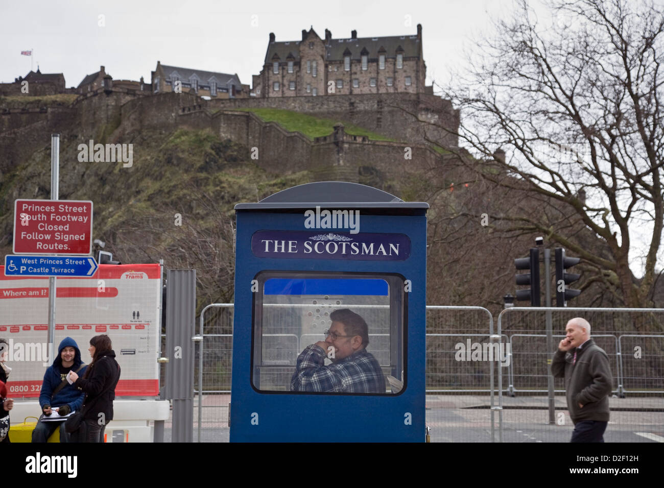 Venditore a vendere lo Scotsman e Edinburgh Evening News quotidiani da una cabina in Princes Street, Edinburgh Foto Stock