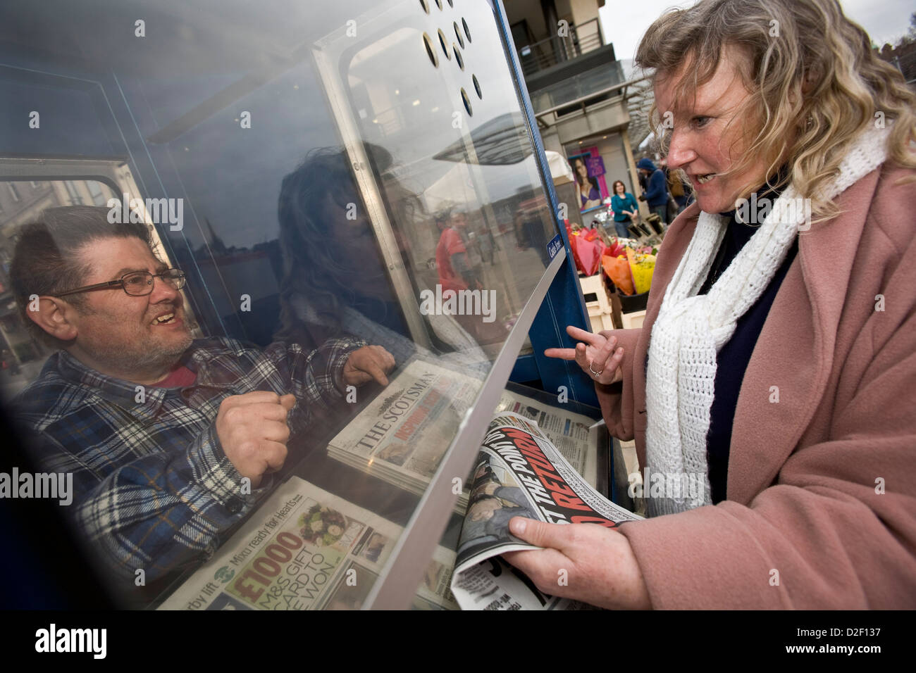 Venditore a vendere lo Scotsman e Edinburgh Evening News quotidiani da una cabina in Princes Street, Edinburgh Foto Stock