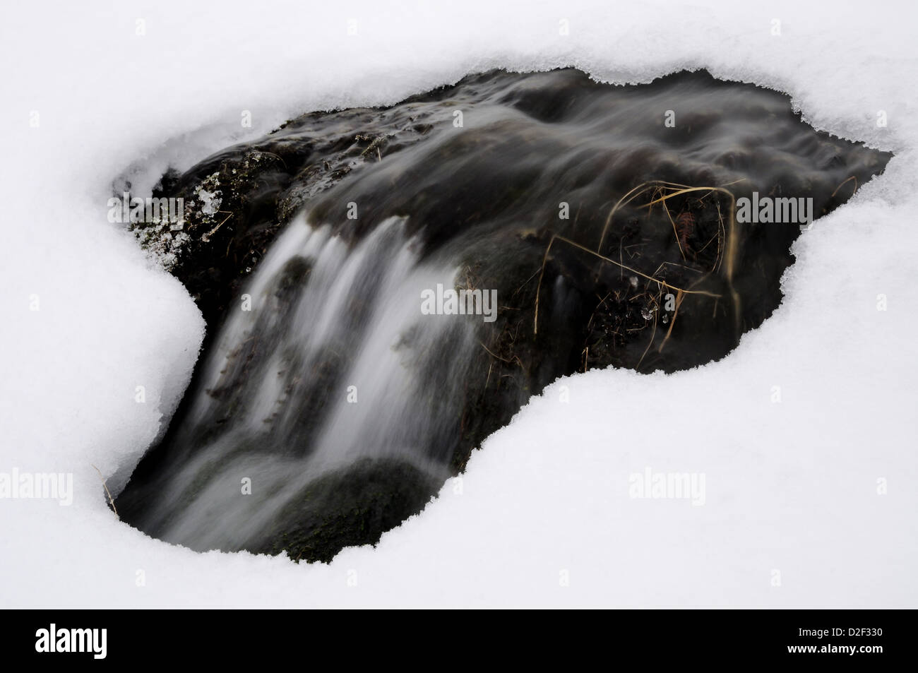 Mini cascata sul pettine Gill inserimenti attraverso uno spazio sotto la neve in inverno nel Lake District inglese Foto Stock
