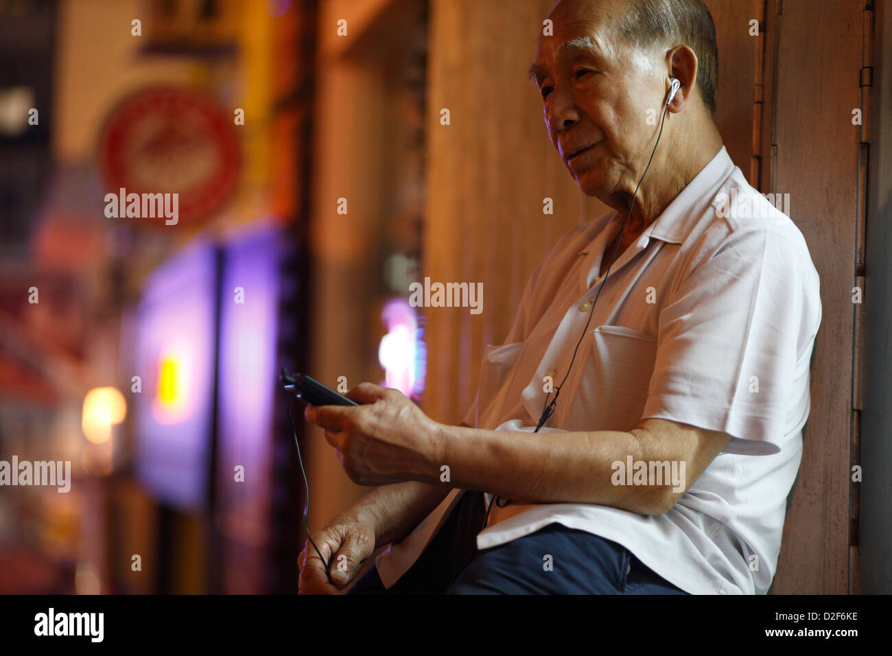 Hong Kong, Cina, un vecchio uomo seduto nelle strade di Hong Kong e ascolta la musica Foto Stock