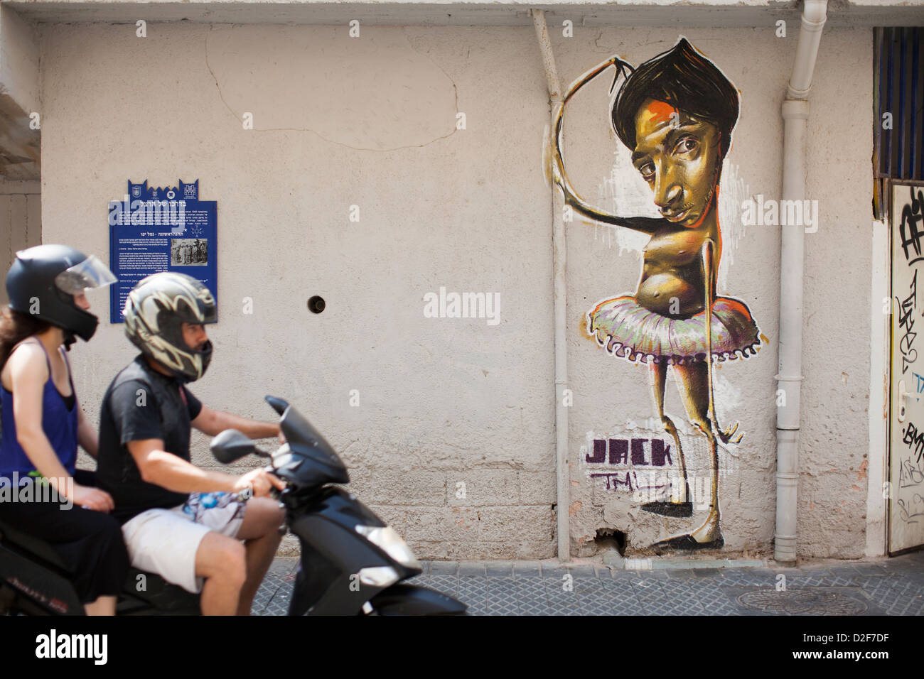 Due persone su un ciclomotore scooter pass street art su una parete in Jaffa, Israele. Foto Stock