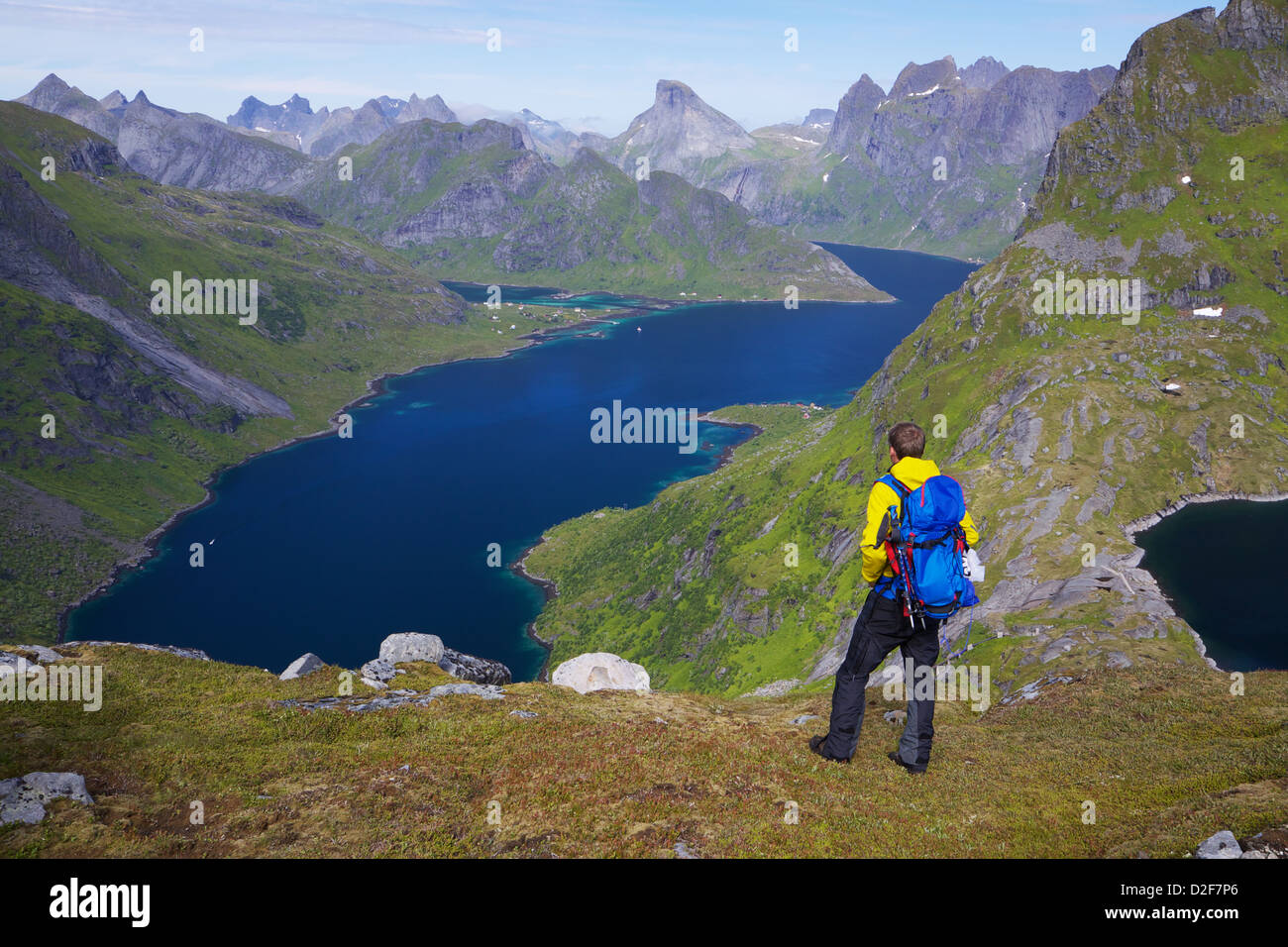 Giovane uomo attivo con zaino escursioni sulle isole Lofoten in Norvegia sulla giornata soleggiata con suggestivo panorama in background Foto Stock