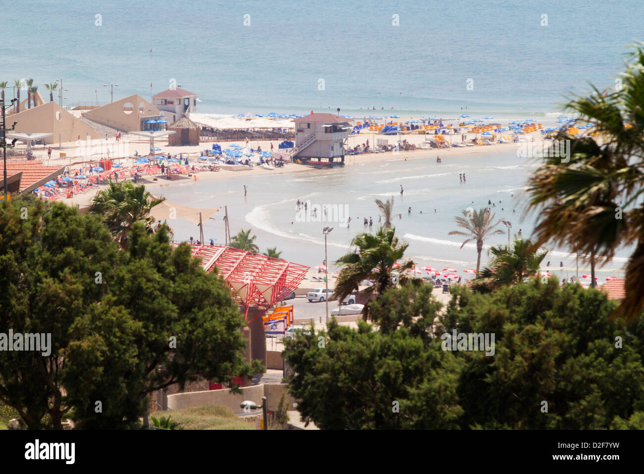 Persone nuotare e fare surf nel Mar Mediterraneo al largo della costa di Israele su una calda giornata di sole con il cielo blu e acque calme. Foto Stock