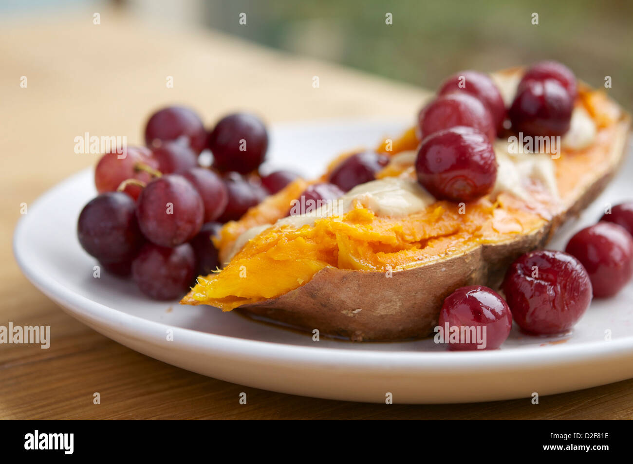 Piastra con arrosto riempito di uva patate dolci con un vegan salsa al formaggio e sciroppo d'acero Foto Stock