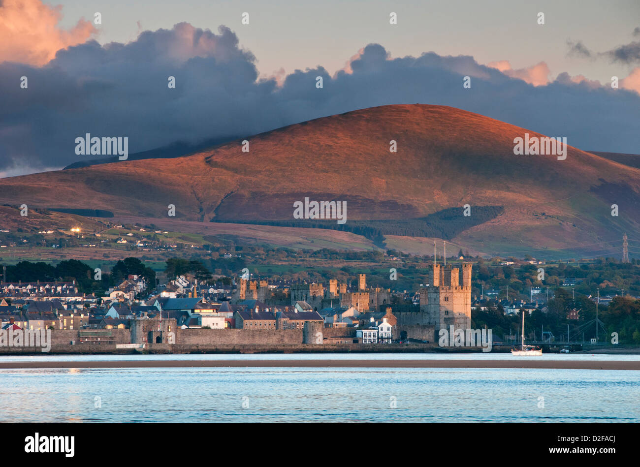 Caernarfon Castle e Menai Straits sostenuta da Moel Eilio, visto da Anglesey, Gwynedd, Galles del Nord, Regno Unito Foto Stock