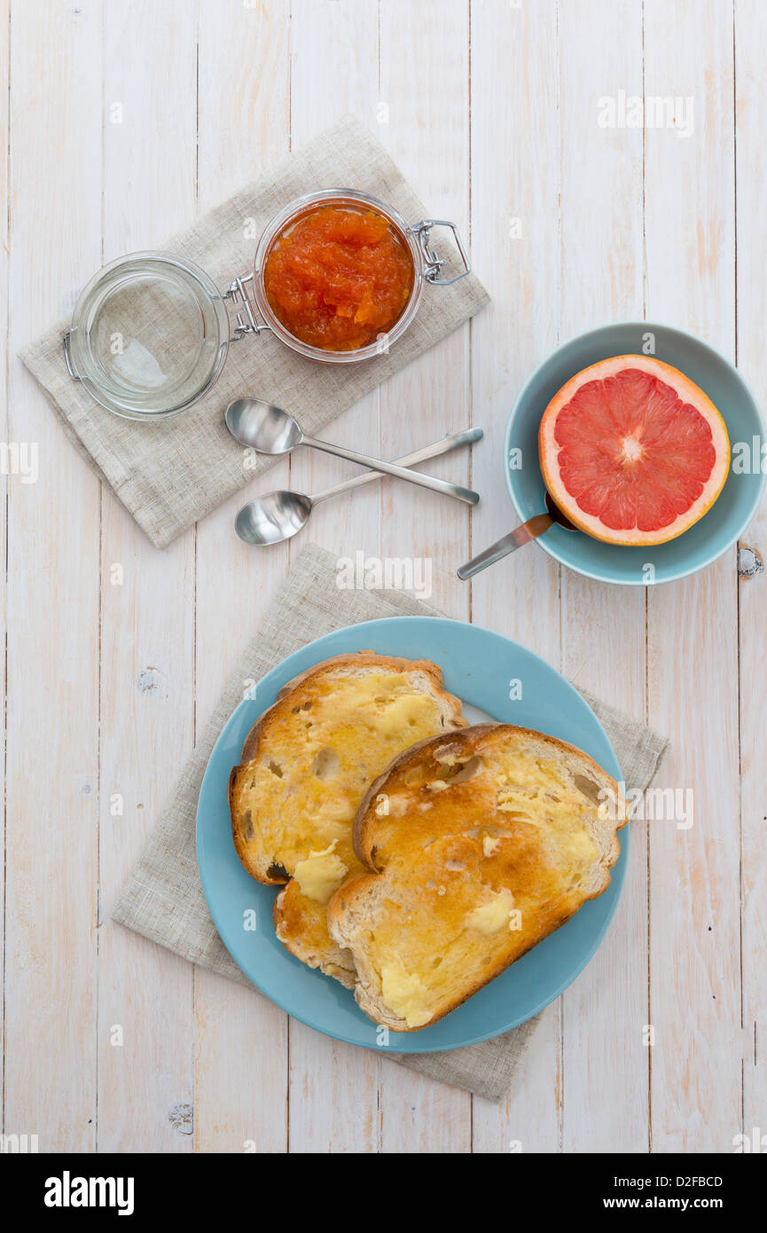 Toast imburrato, con una mezza pompelmo rosa, e marmellata. Foto Stock