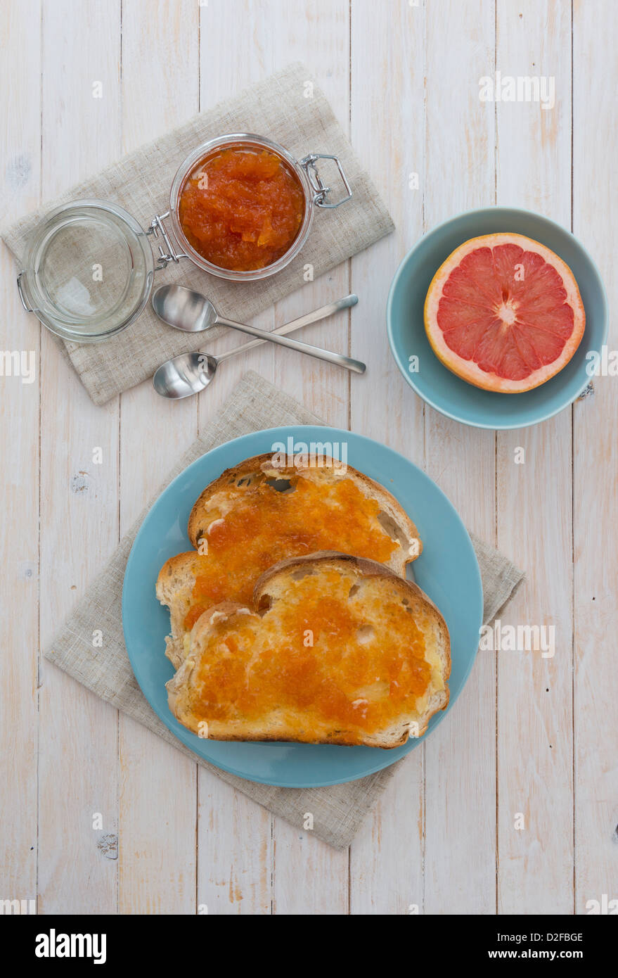Pompelmo rosa marmellata sul pane tostato, con una mezza pompelmo rosa. Foto Stock