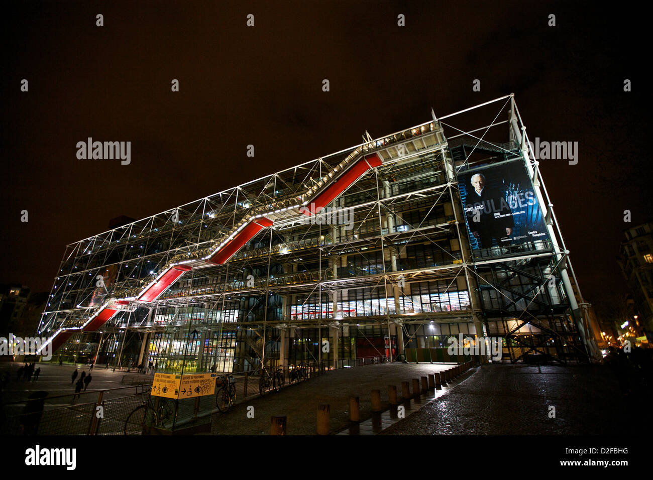 Il Centre Pompidou, illuminato di notte a Parigi, Francia, mostra la sua iconica architettura moderna con scale mobili rosse e pannelli di vetro Foto Stock