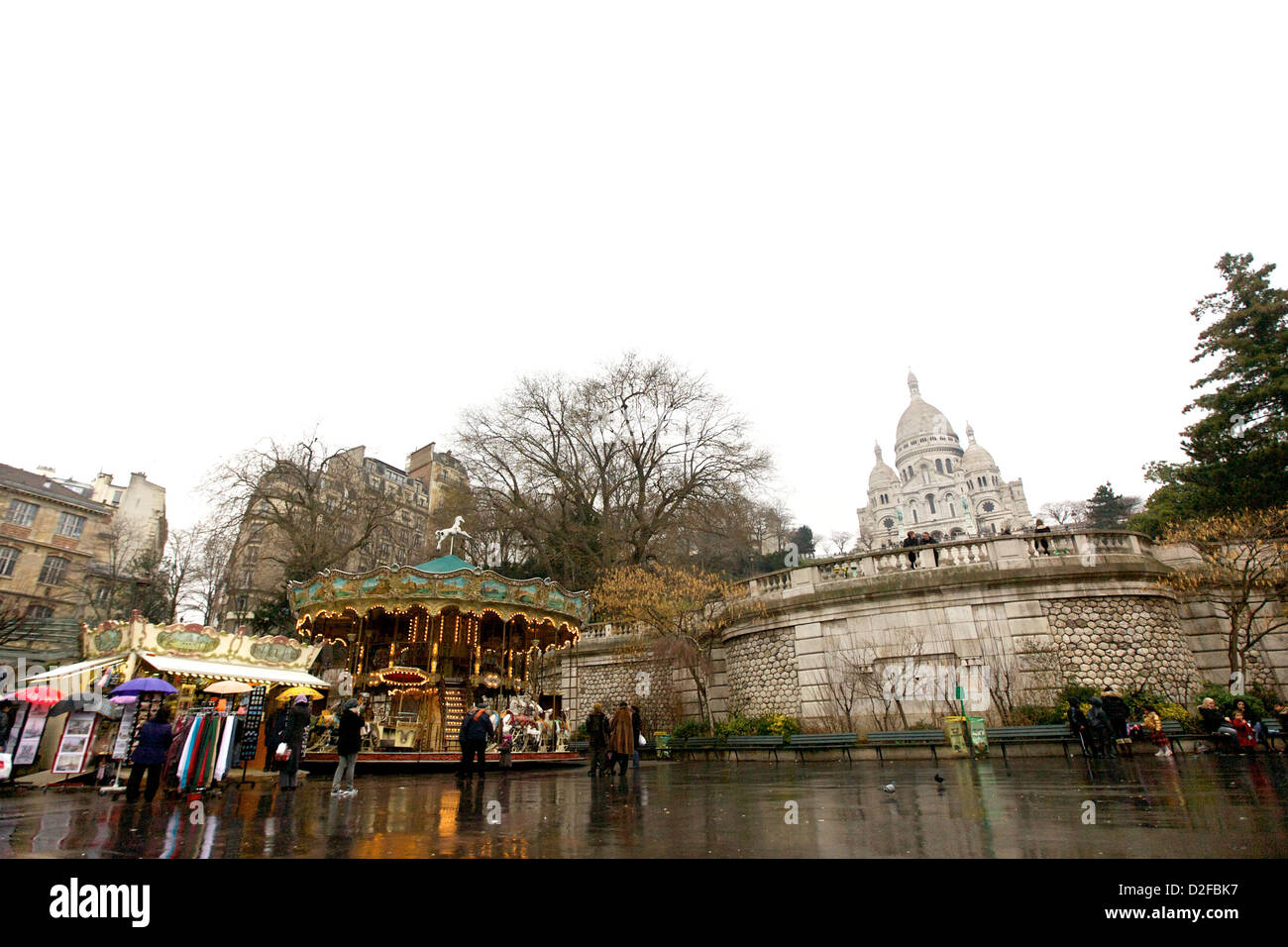 Una giornata di pioggia a Montmartre, Parigi, Francia, con l'iconica basilica del Sacro Cœur e un'affascinante giostra in primo piano Foto Stock