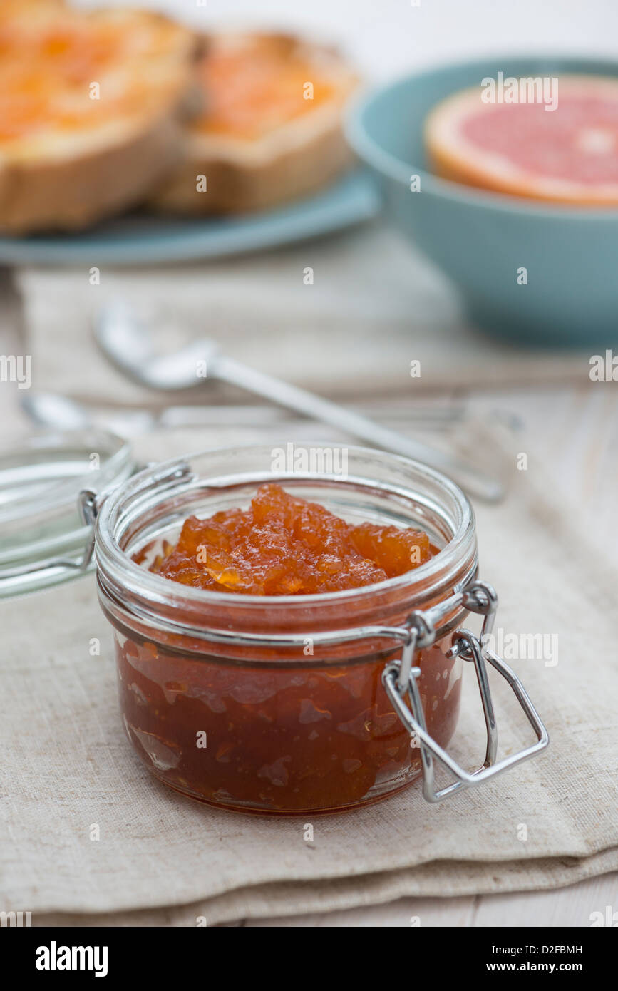 Pompelmo rosa marmellata sul pane tostato, con una mezza pompelmo rosa. Foto Stock