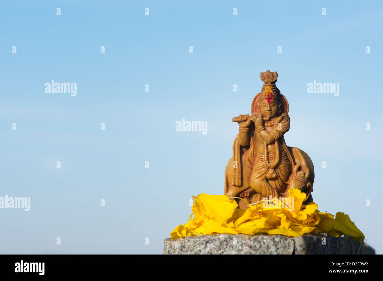 Krishna statua e petali di fiori contro un cielo blu. India Foto Stock