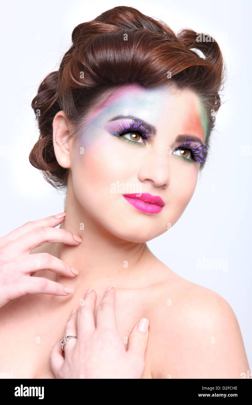Donna con colorati cosmetici creativi su bianco Foto Stock