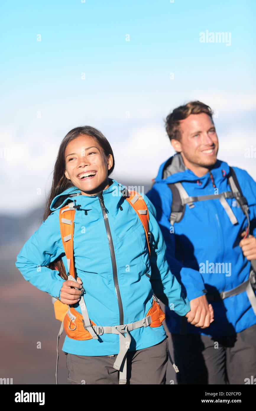 Giovane sportivo felice interracial escursionismo coppia tenendo le mani sulla montagna escursione a piedi al di fuori in alta montagna Foto Stock