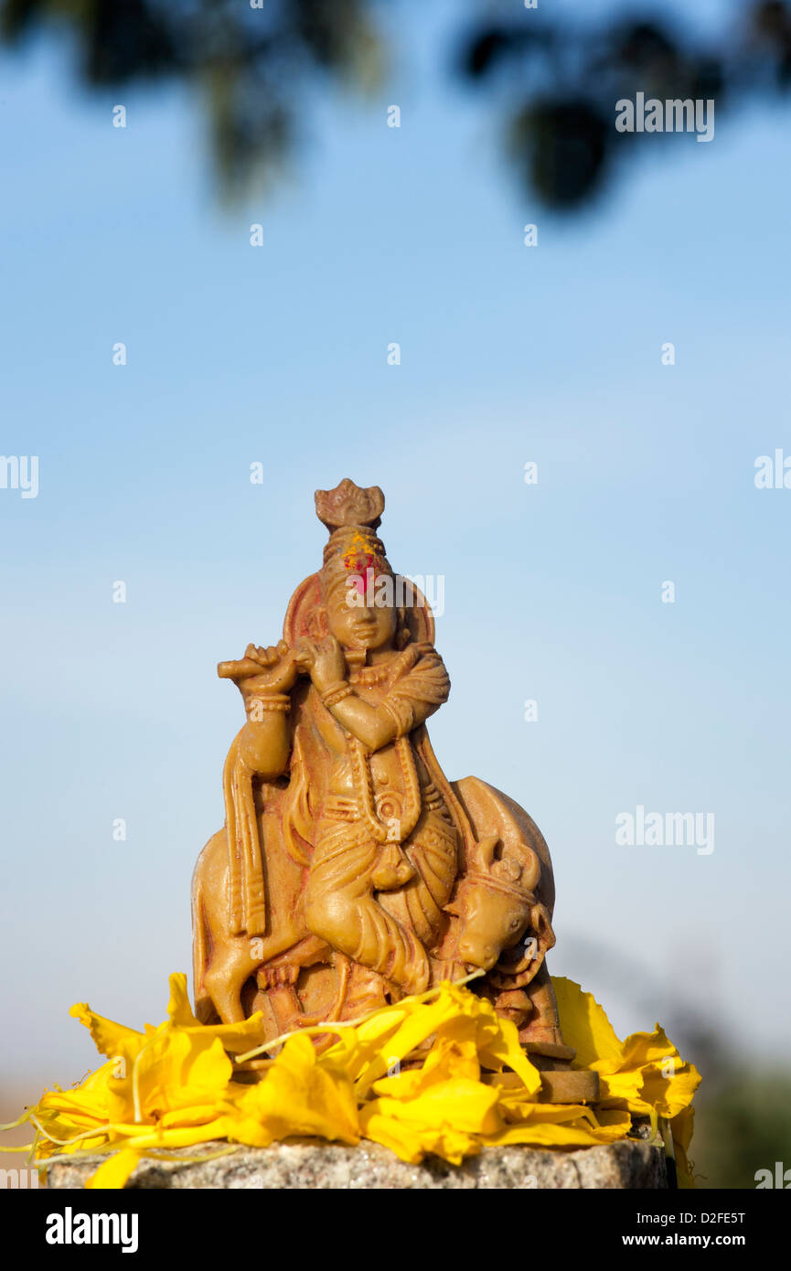 Krishna statua e petali di fiori contro un cielo blu. India Foto Stock