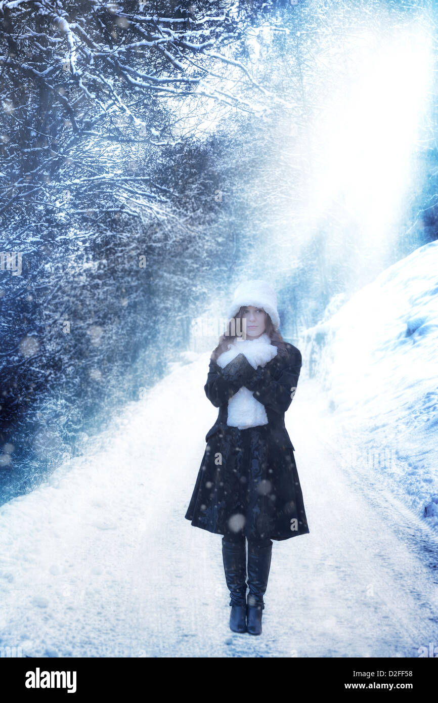 Una donna in un manto nero è in piedi su una strada di inverno Foto Stock