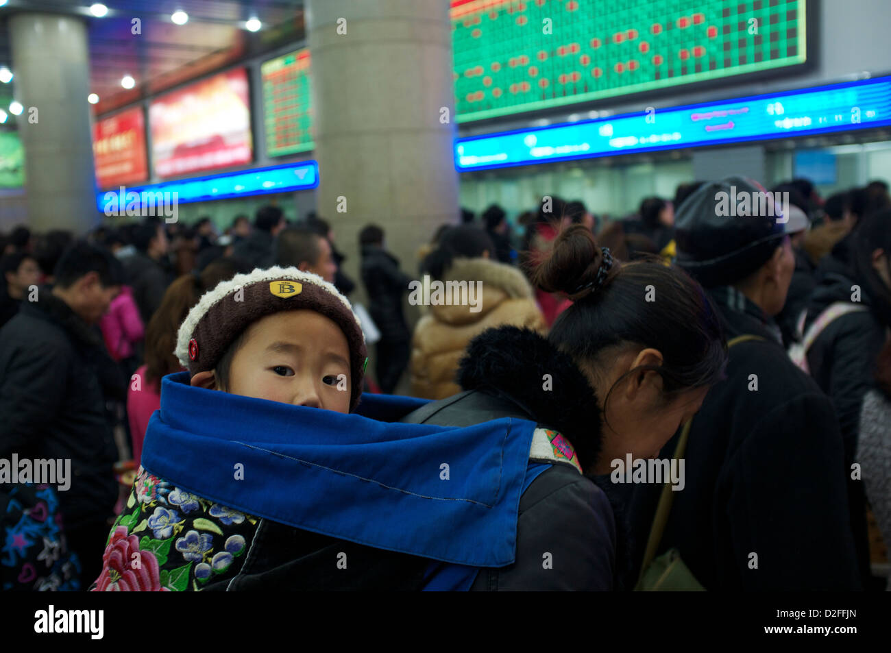 Una madre cinese tenendo un bambino sulla schiena coda per acquistare un biglietto del treno in corrispondenza di una Stazione Ferroviaria di Beijing in Cina. 22-Gen-2013 Foto Stock