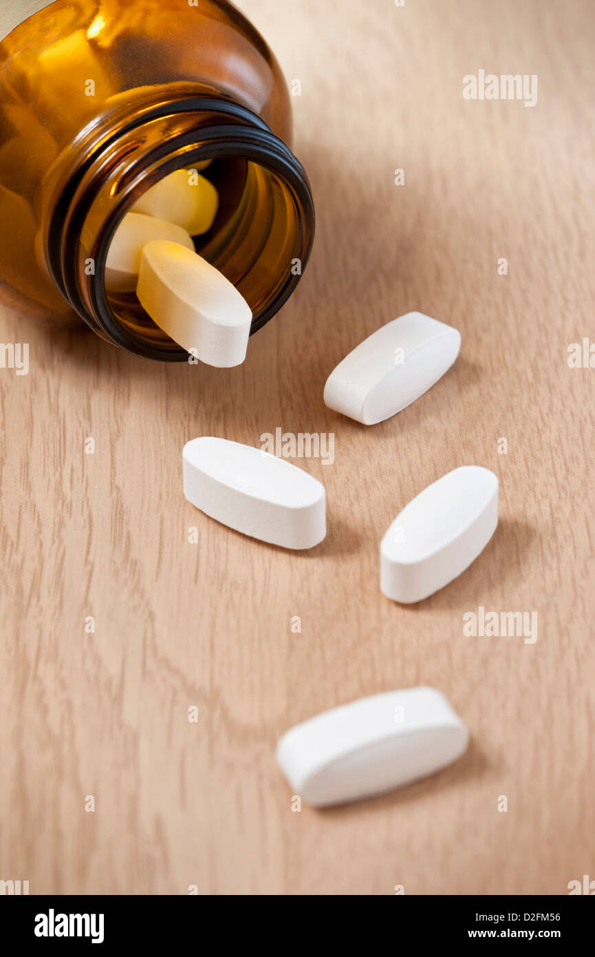 Pills bottiglia con alcuni fuoriuscita sul tavolo Foto Stock