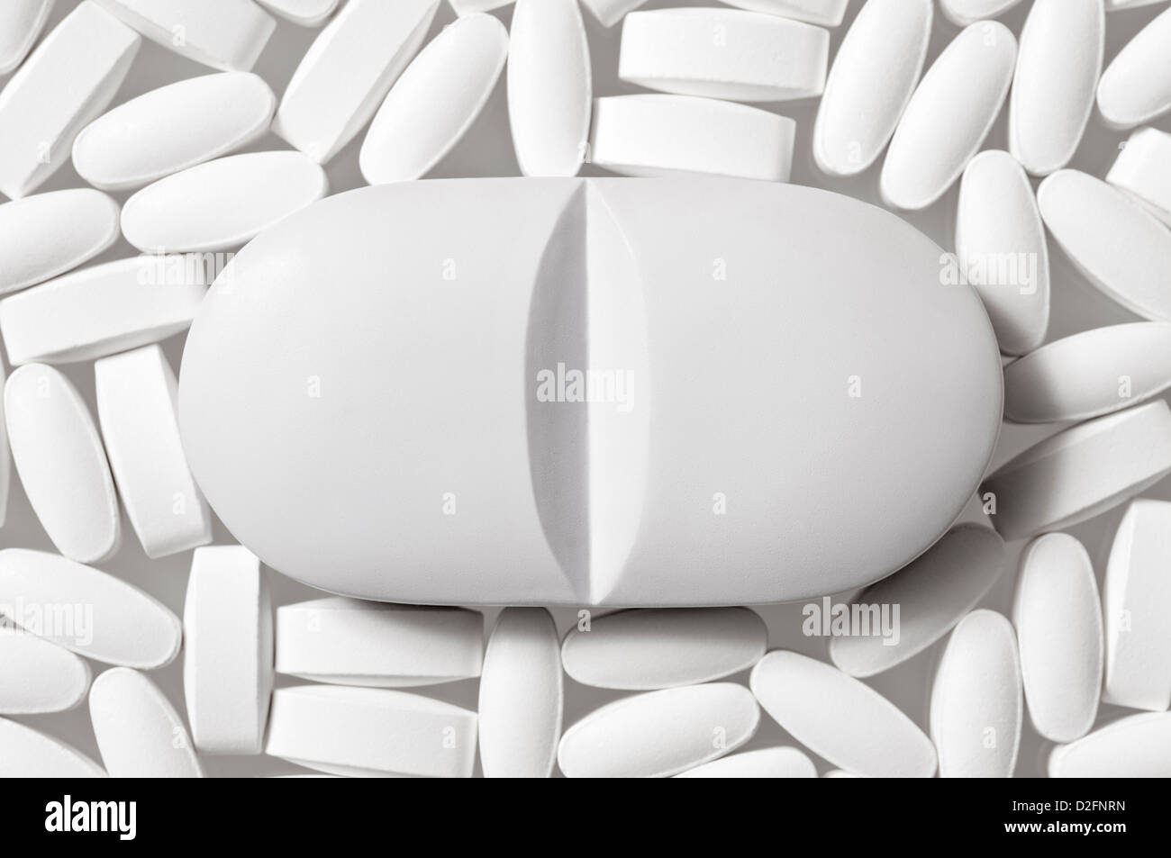 Pillole - generico bianco a forma di losanga pillole in bianco su sfondo bianco con una pillola di grandi dimensioni nel centro Foto Stock
