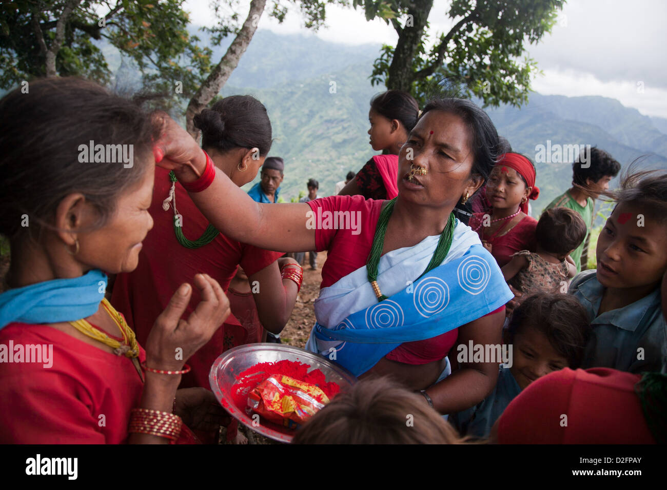 Sanamaya Chepang sta dando Tika alle persone a un raduno in montagna, una tradizione indù significato buona fortuna e salute. Foto Stock