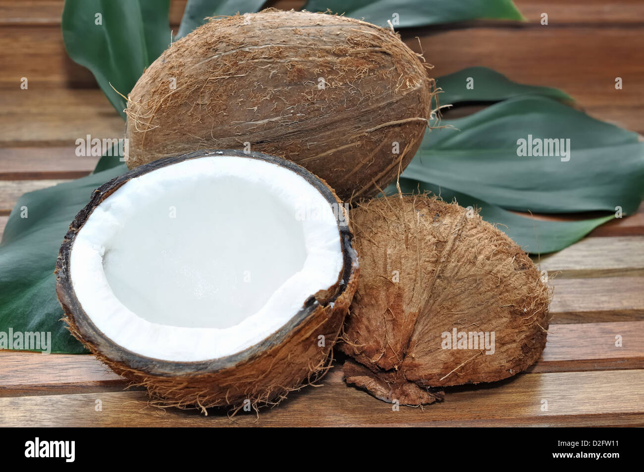 Il cocco aperto su una foglia su sfondo di legno Foto Stock