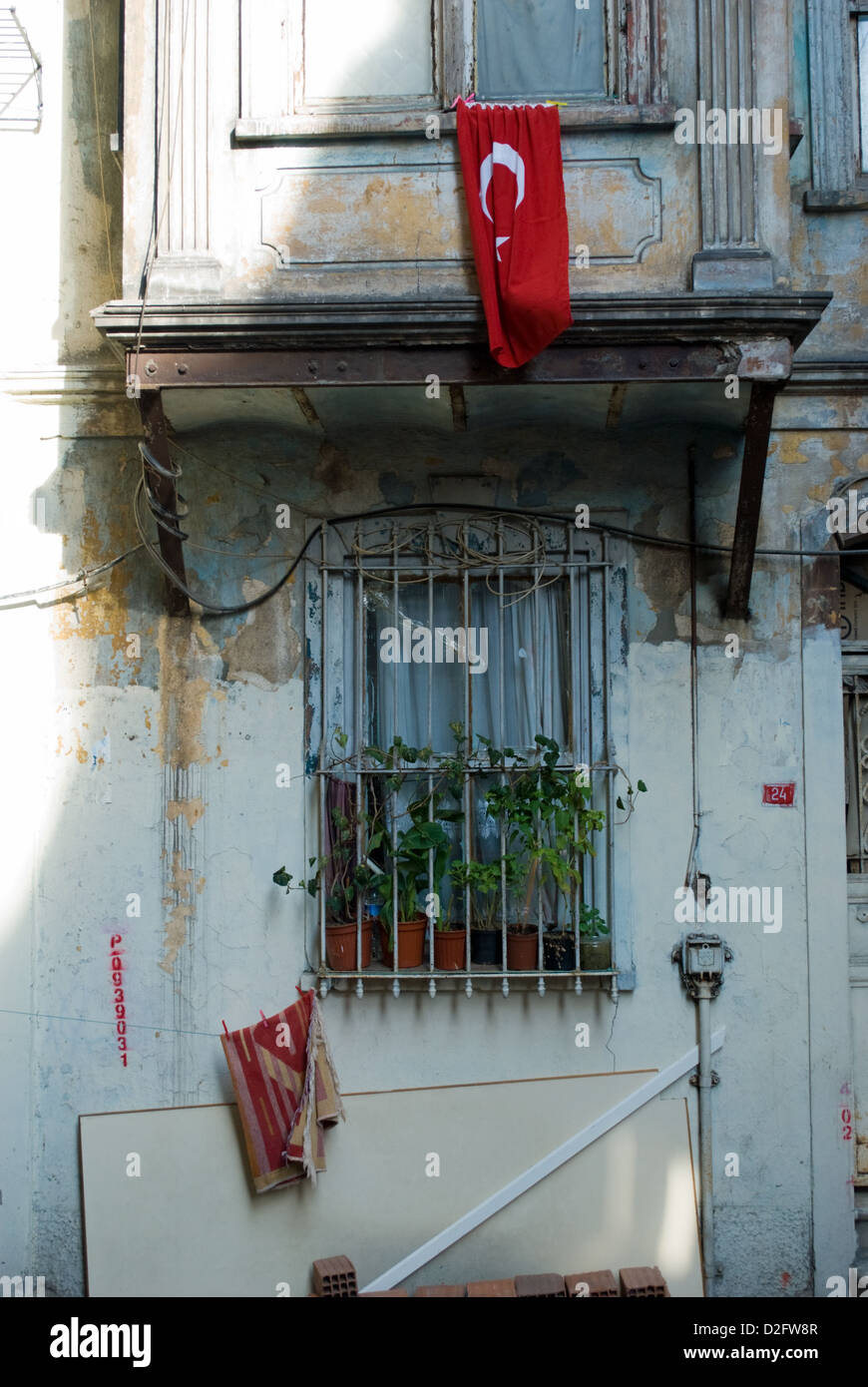 Una bandiera turca pende dalla finestra della casa di poveri prevalentemente curda del distretto Tarlabasi, Istanbul. Foto Stock