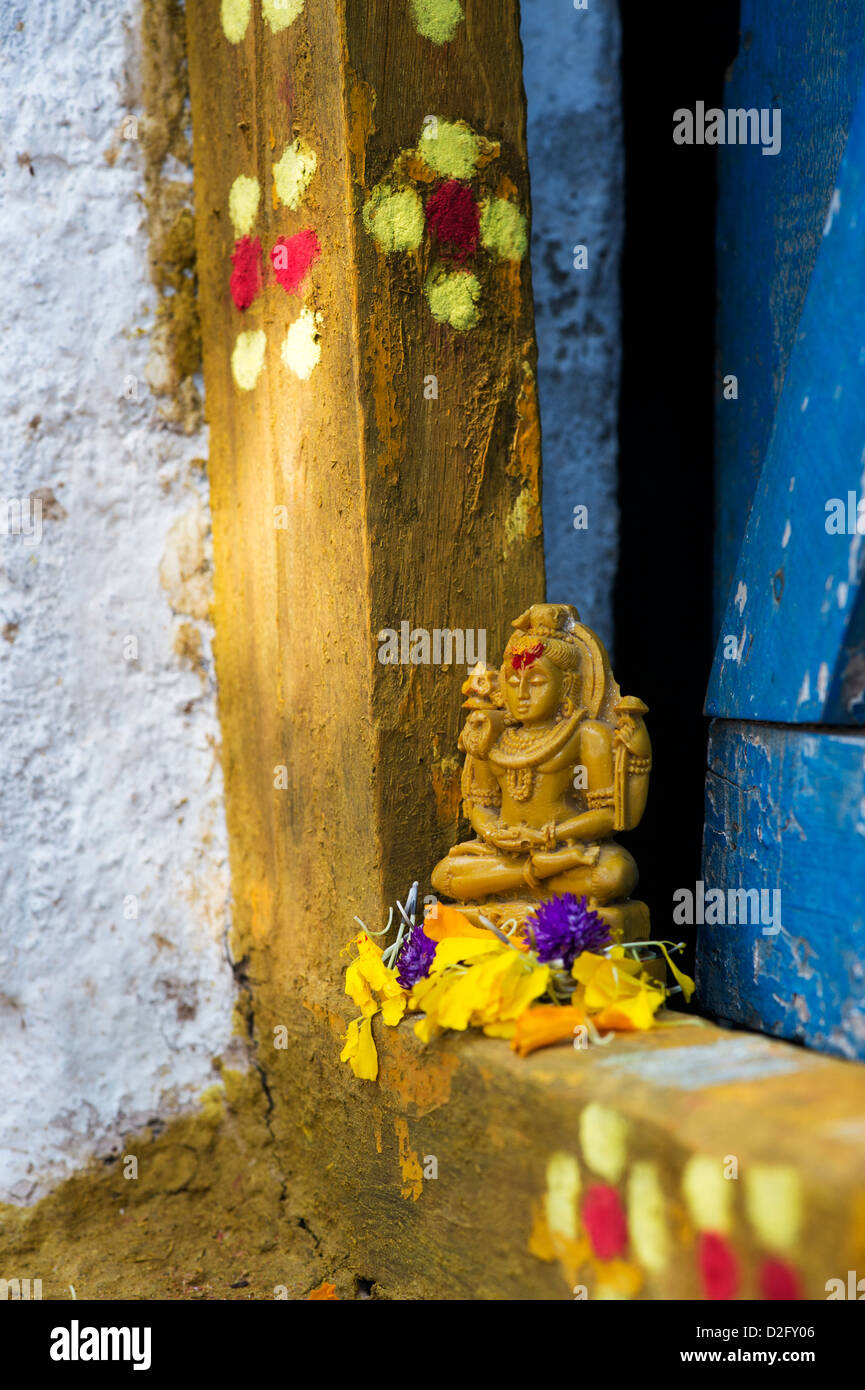 Signore Shiva statua e petali di fiori al di fuori del tempio del villaggio porta. India Foto Stock