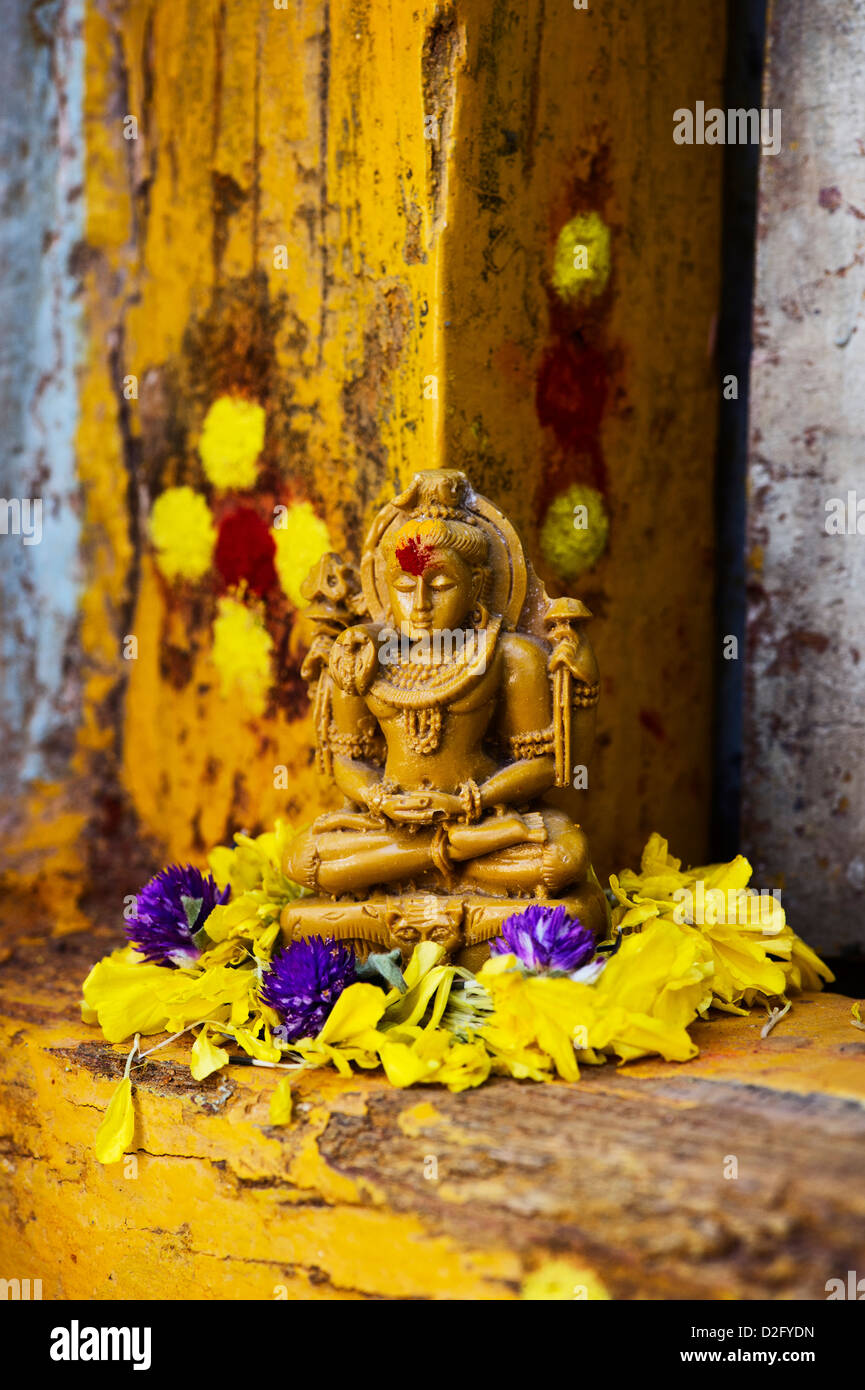 Signore Shiva statua e petali di fiori al di fuori del tempio del villaggio porta. India Foto Stock