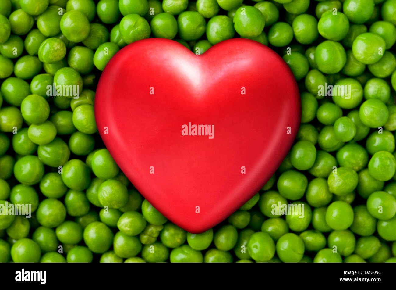 Cibo sano - cuore rosso su freschi piselli verdi Foto Stock