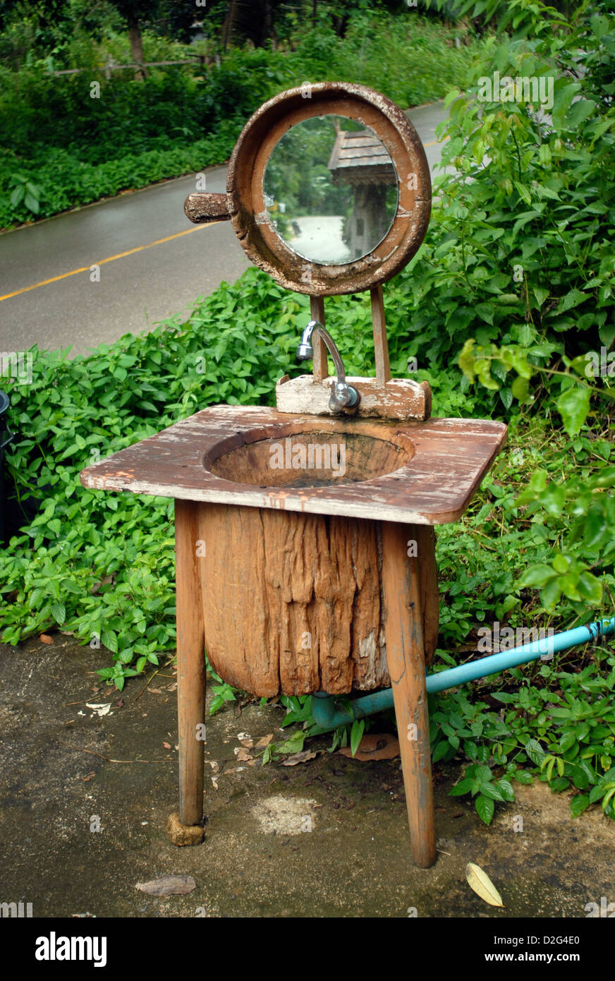 Un dissipatore di lavoro realizzato da un vecchio scavato tronco di albero con uno specchio lungo il lato della strada in Koh Chang thailandia Foto Stock