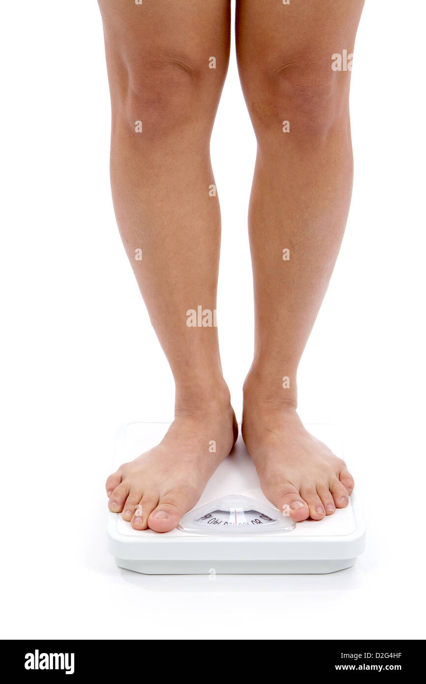 Donna di abbassare le gambe e piedi mostrato su una bilancia da bagno per weightloss concetto. Foto Stock