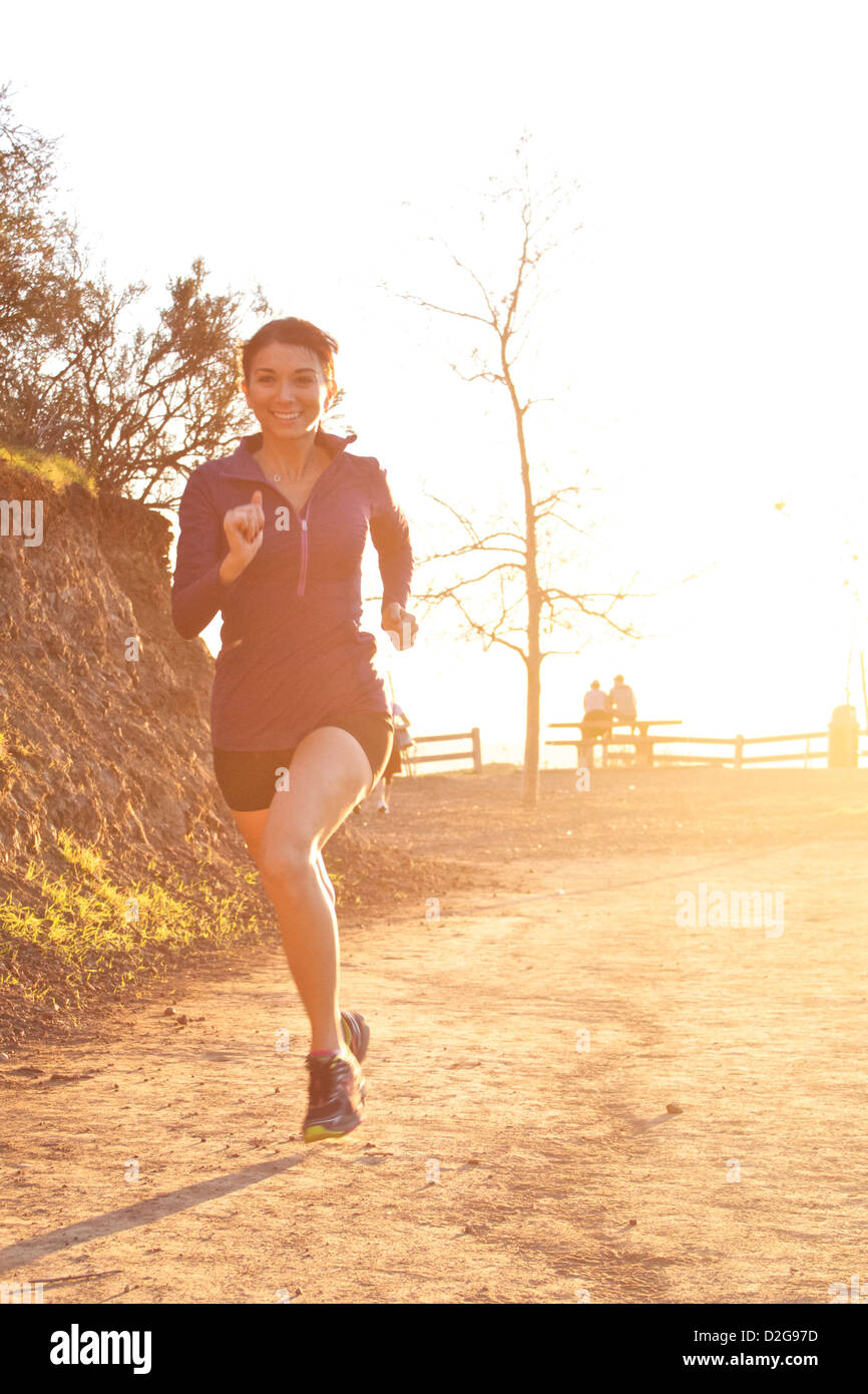 Una giovane donna ama il trail running a Griffith Park, Los Angeles, California, crogiolandosi alla luce dorata del sole Foto Stock