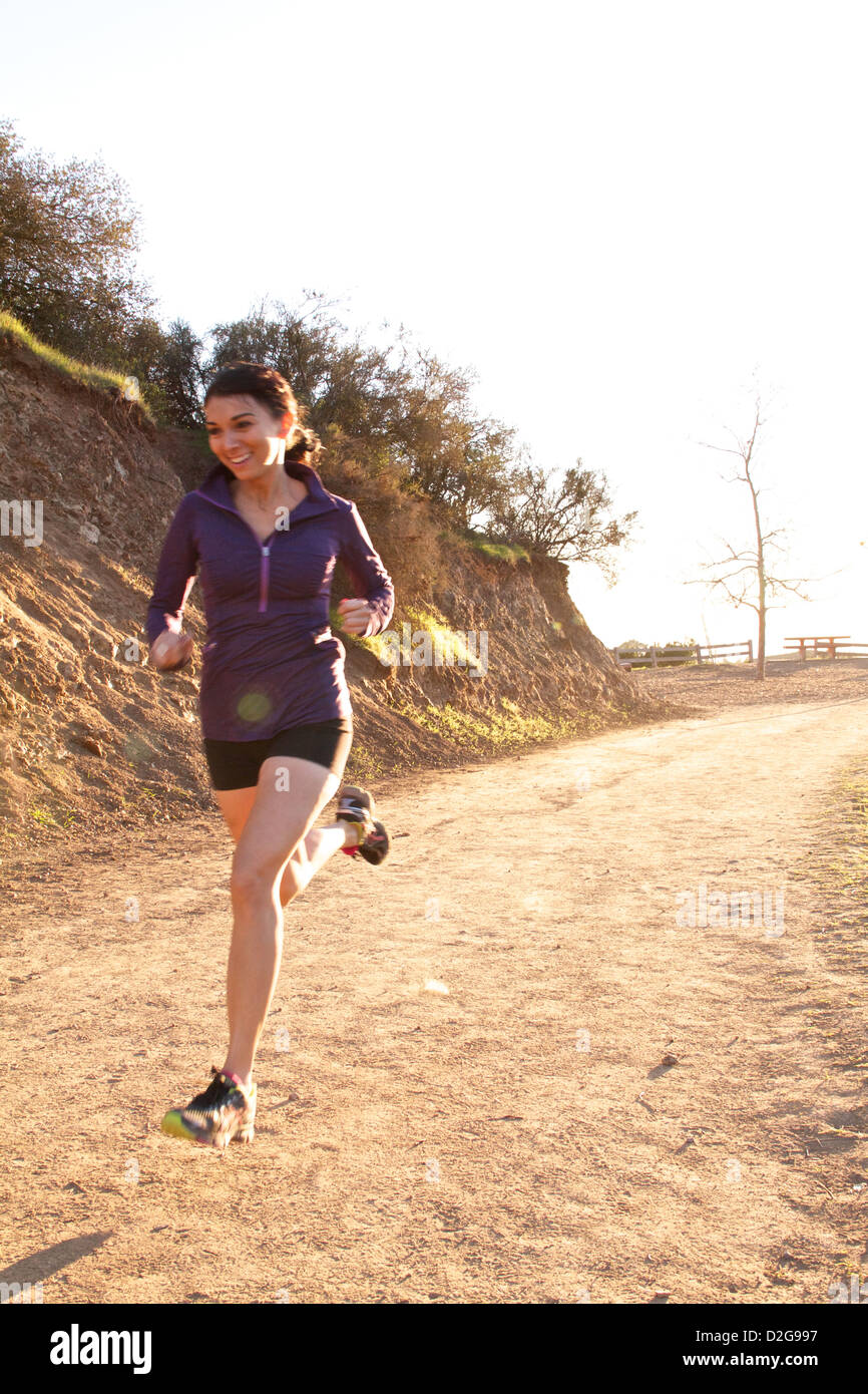 Una giovane donna ama il trail running a Griffith Park, Los Angeles, California, crogiolandosi alla luce dorata del sole Foto Stock