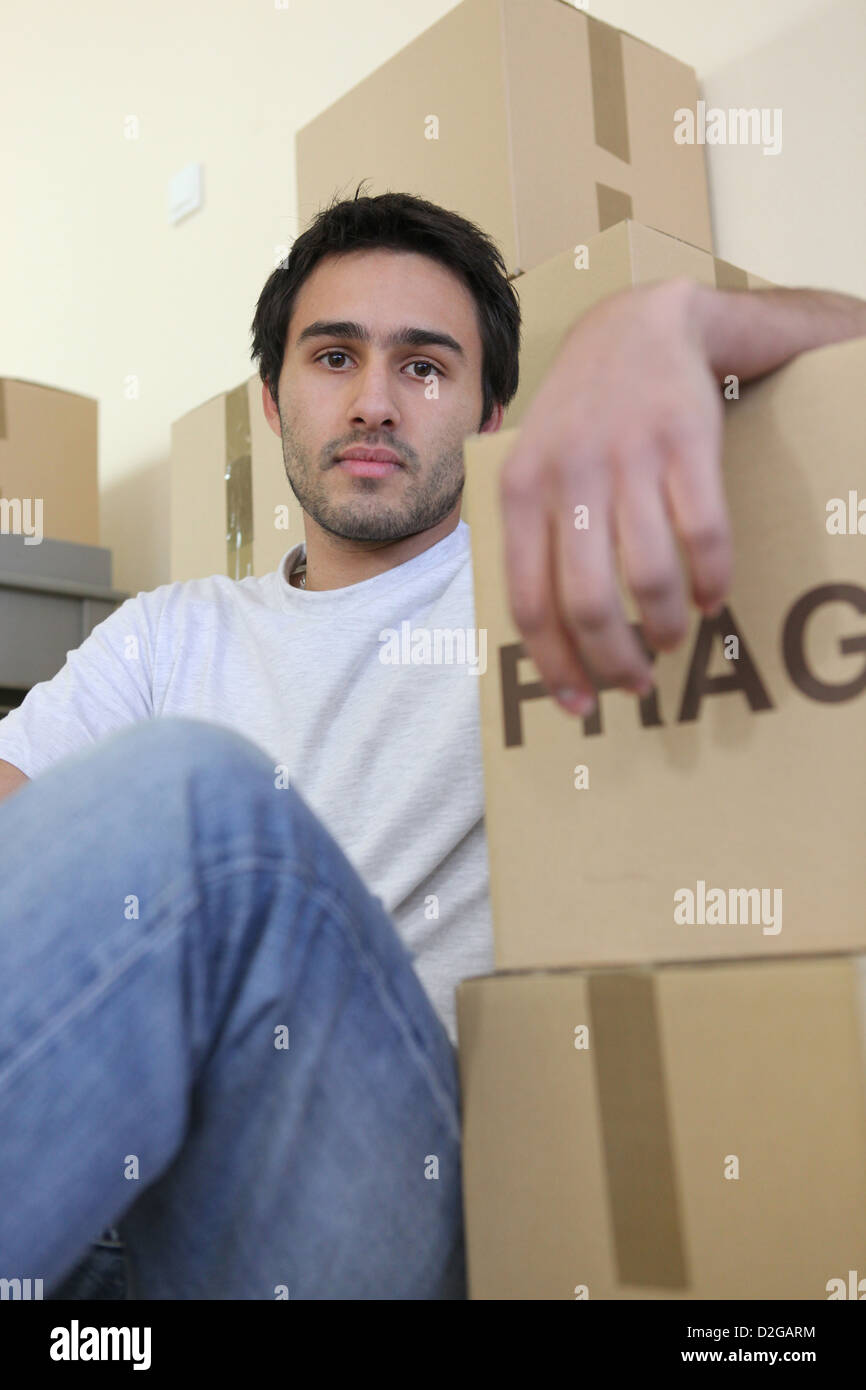 Giovane uomo circondato da scatole di cartone sul giorno del trasloco Foto Stock