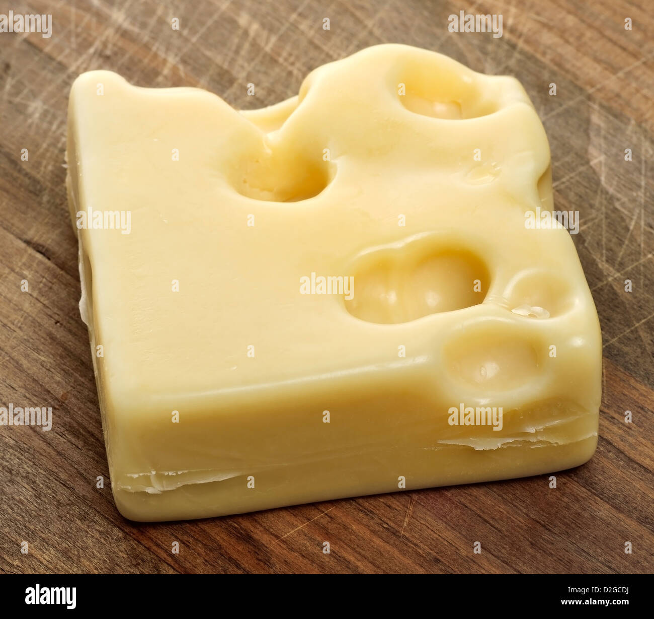 Pezzo di formaggio svizzero con fori su un tagliere Foto Stock