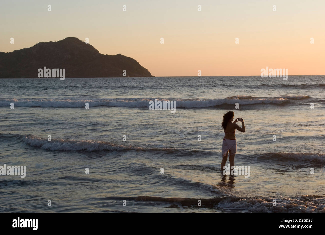 Giovane donna prendendo le foto digitali al tramonto, Mazatlan, Sinaloa Membro, Messico. Foto Stock